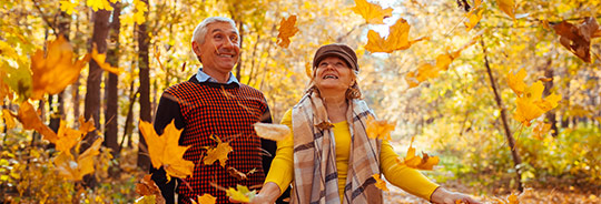 photo of couple standing under falling leaves